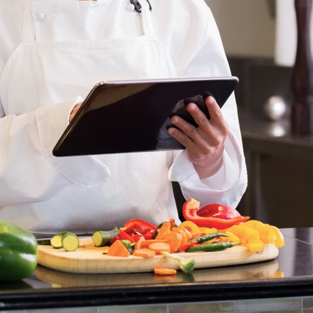 Chef using tablet while preparing colorful vegetables