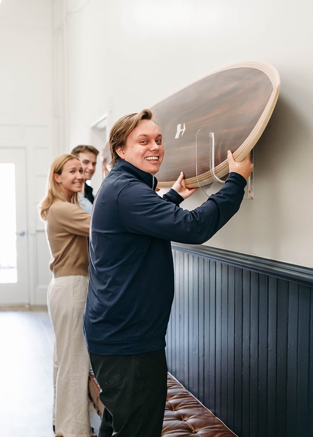 Group hanging wooden surfboard on wall indoors