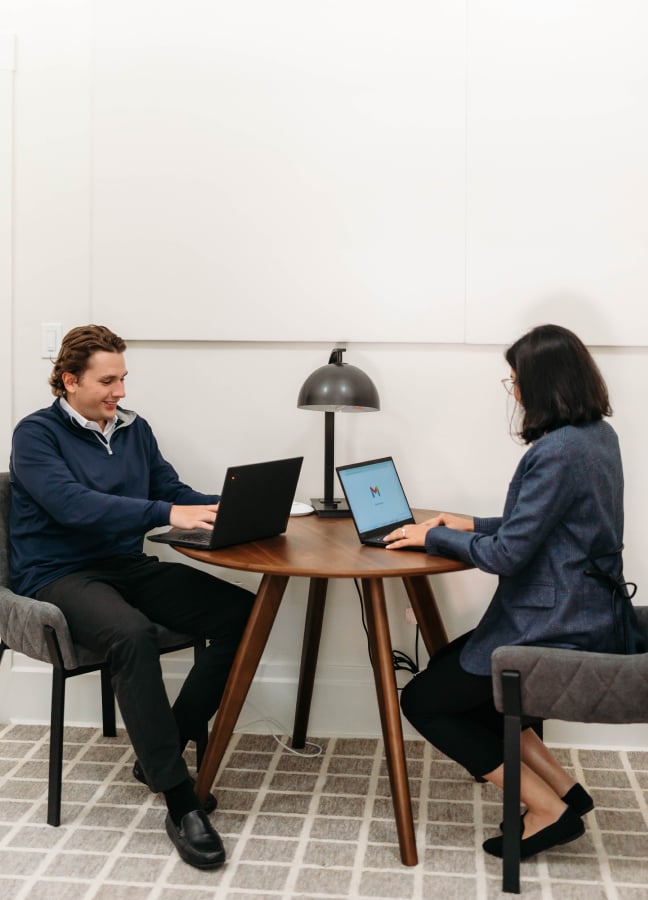 Two people working on laptops at table