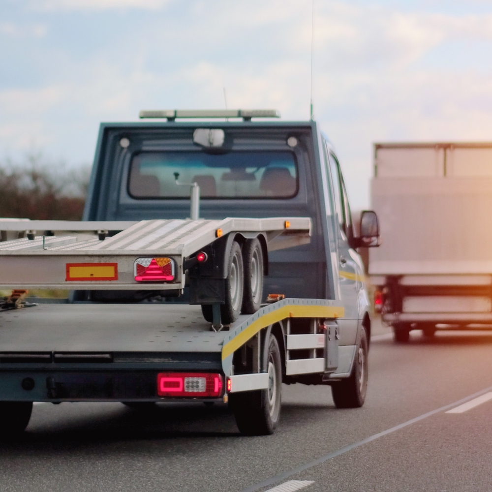 Tow truck driving on highway at sunset