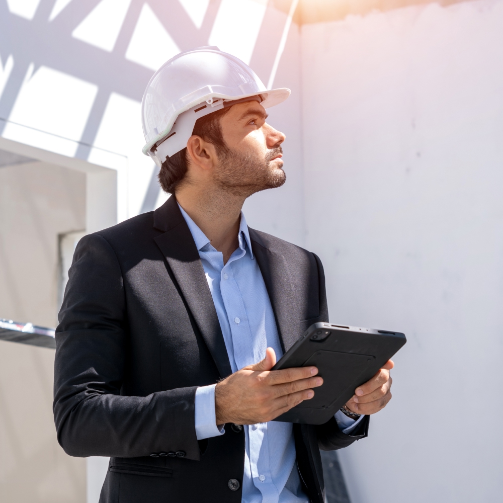 Construction engineer examining building site with tablet