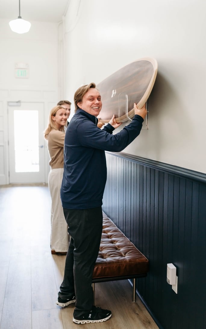 People mounting wooden object on wall together